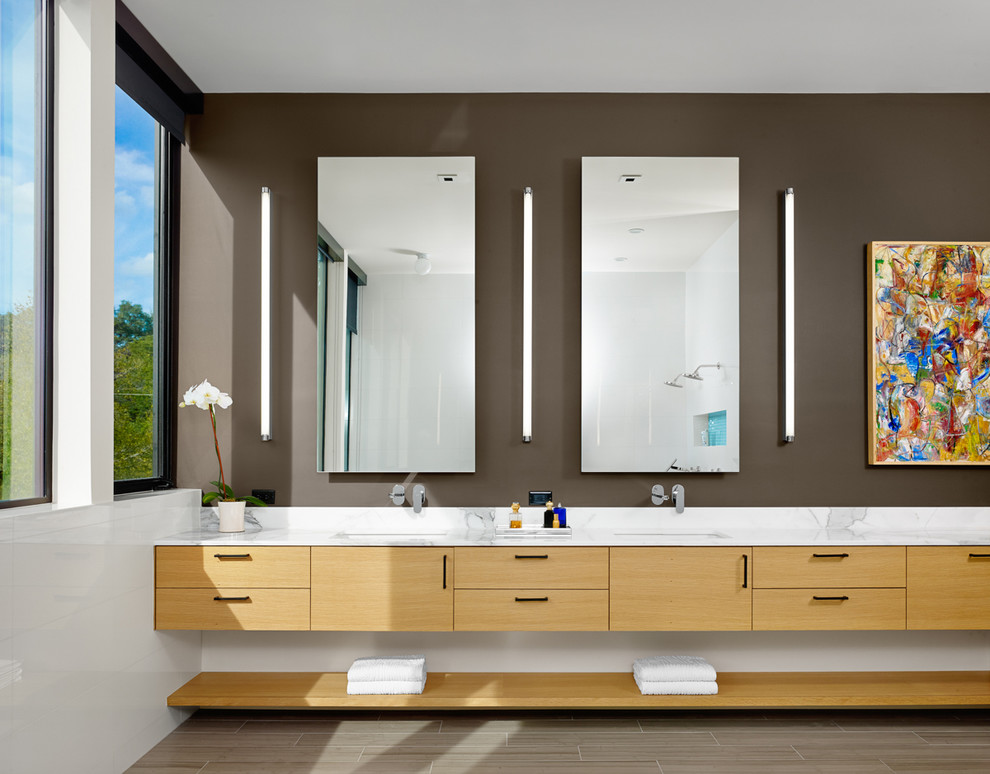This is an example of a contemporary bathroom in Austin with an undermount sink, flat-panel cabinets, medium wood cabinets, white tile, brown walls and white benchtops.