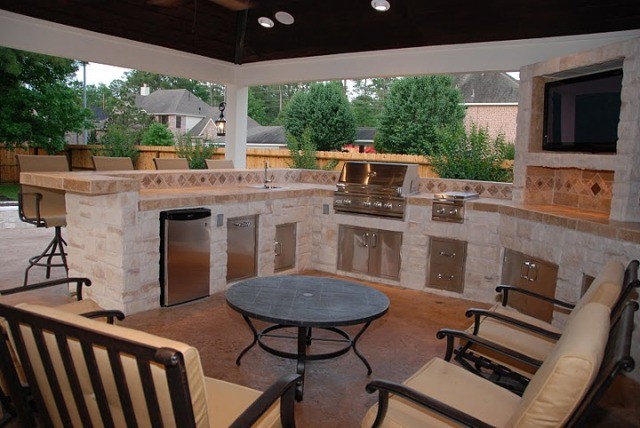 Design ideas for a contemporary backyard patio in Houston with an outdoor kitchen, stamped concrete and a roof extension.