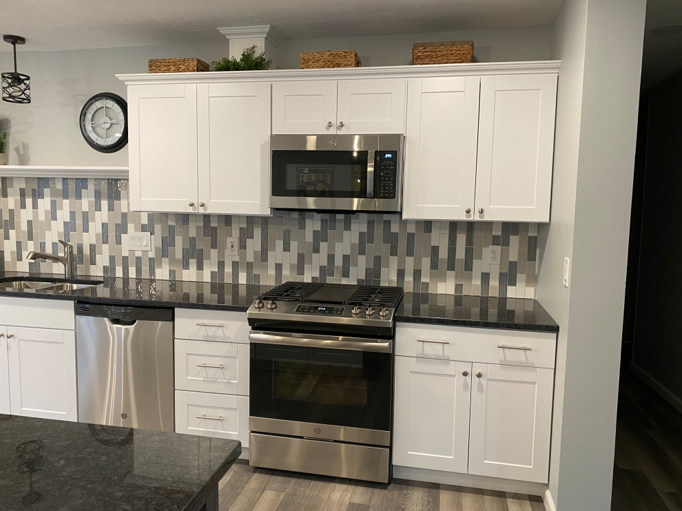 Example of a large transitional l-shaped vinyl floor and gray floor open concept kitchen design in Cincinnati with an undermount sink, raised-panel cabinets, white cabinets, granite countertops, multicolored backsplash, ceramic backsplash, stainless steel appliances, an island and black countertops