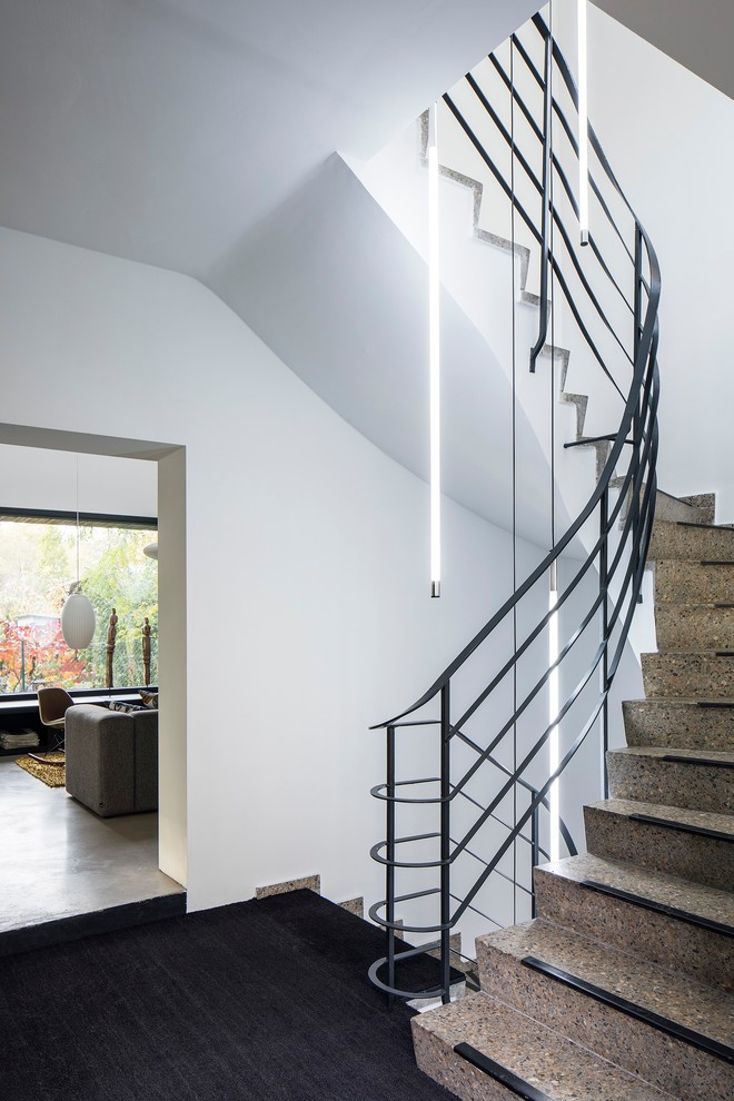 Inspiration for a mid-sized industrial curved staircase in Berlin with metal railing.