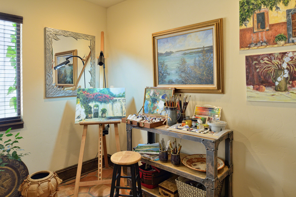 Mediterranean home studio in Austin with beige walls, terra-cotta floors, no fireplace and a freestanding desk.