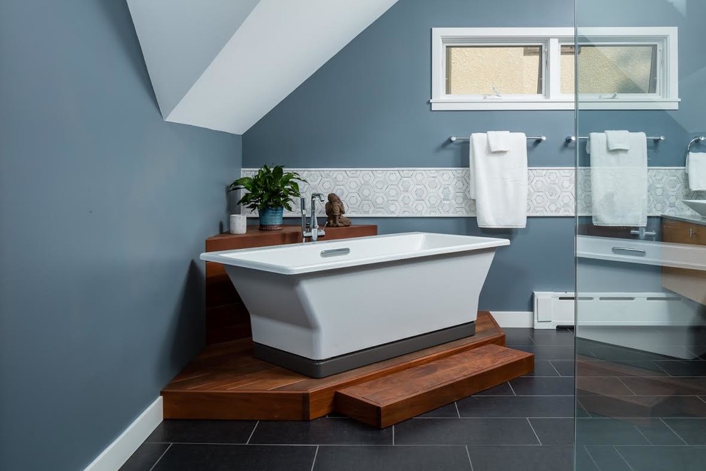 Inspiration for a mid-sized contemporary master bathroom in Minneapolis with flat-panel cabinets, light wood cabinets, a freestanding tub, a curbless shower, blue walls, a vessel sink and black floor.