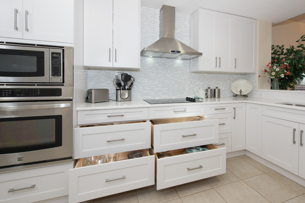 Design ideas for a large contemporary l-shaped eat-in kitchen in Tampa with a double-bowl sink, recessed-panel cabinets, white cabinets, white splashback, matchstick tile splashback, stainless steel appliances, porcelain floors and no island.