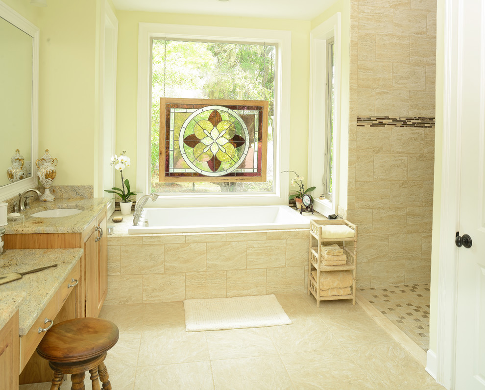 Inspiration for a mid-sized country master bathroom in Charleston with an undermount sink, raised-panel cabinets, dark wood cabinets, granite benchtops, a drop-in tub, an open shower, a two-piece toilet, beige tile, stone slab and porcelain floors.
