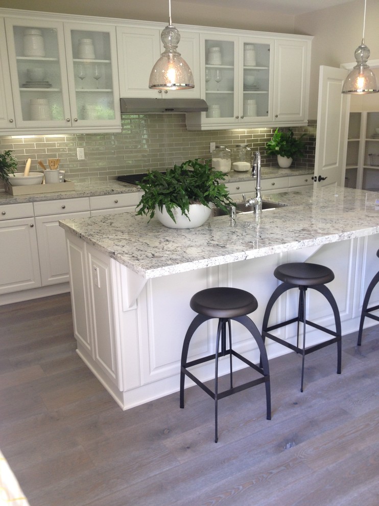 Example of a trendy l-shaped gray floor kitchen design with a drop-in sink, white cabinets, gray backsplash, stainless steel appliances and an island
