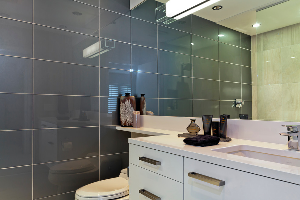 Design ideas for a small contemporary 3/4 bathroom in Minneapolis with an undermount sink, flat-panel cabinets, white cabinets, engineered quartz benchtops, a curbless shower, a one-piece toilet, gray tile, glass tile, multi-coloured walls and porcelain floors.