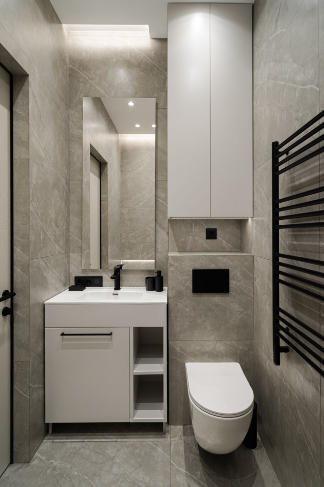 Inspiration pour une salle de bain principale et grise et blanche design de taille moyenne avec un placard à porte plane, des portes de placard grises, une baignoire en alcôve, WC suspendus, un carrelage gris, des carreaux de porcelaine, un mur gris, un sol en carrelage de céramique, un lavabo encastré, un plan de toilette en surface solide, un sol gris, un plan de toilette blanc et meuble simple vasque.