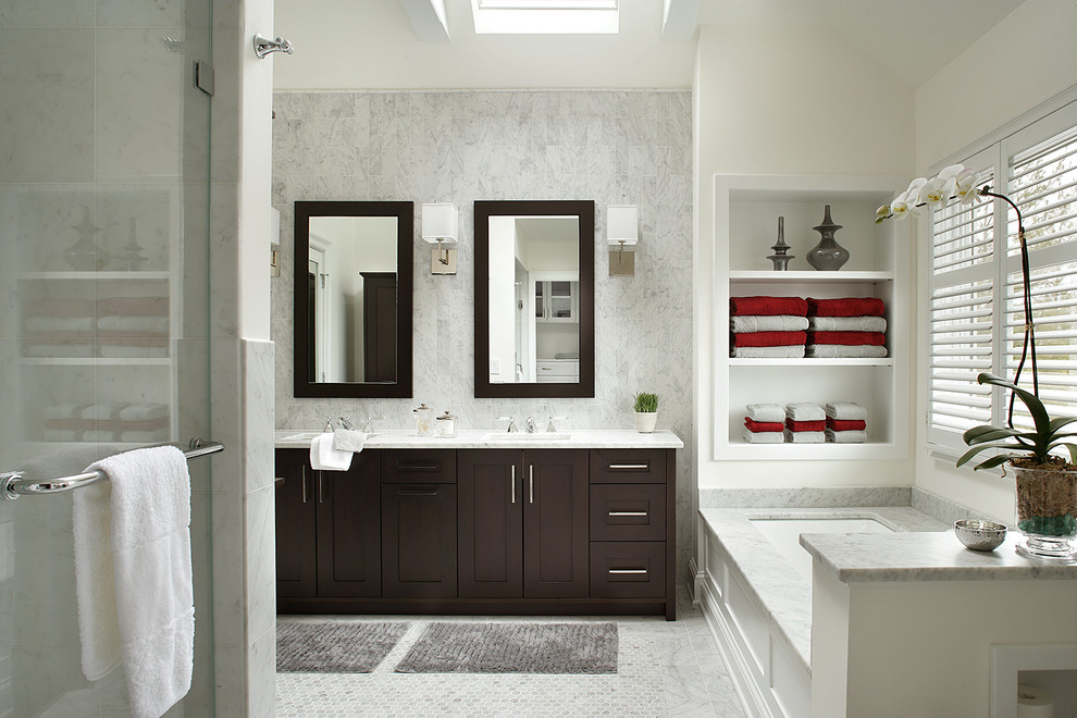 This is an example of a transitional bathroom in New York with shaker cabinets, dark wood cabinets, white tile and an undermount tub.