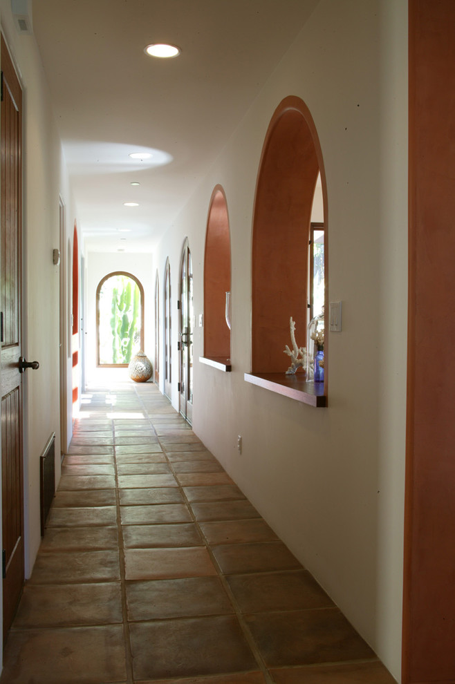 This is an example of a mid-sized mediterranean hallway in Orange County with terra-cotta floors and multi-coloured walls.