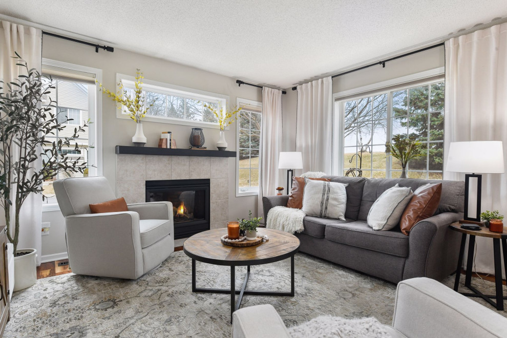 Small transitional living room in Minneapolis with grey walls, laminate floors, a standard fireplace, a tile fireplace surround and brown floor.