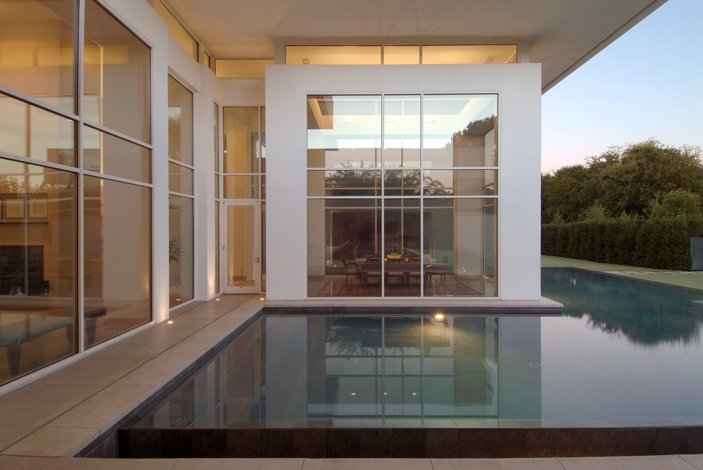 Photo of a mid-sized modern backyard infinity pool in Dallas with concrete pavers.