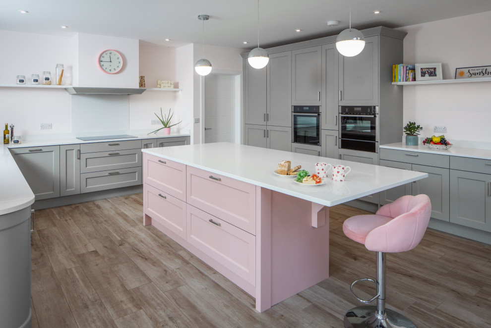 Photo of a large transitional u-shaped open plan kitchen in Other with an undermount sink, shaker cabinets, pink cabinets, quartzite benchtops, white splashback, glass sheet splashback, black appliances, ceramic floors, with island and white benchtop.