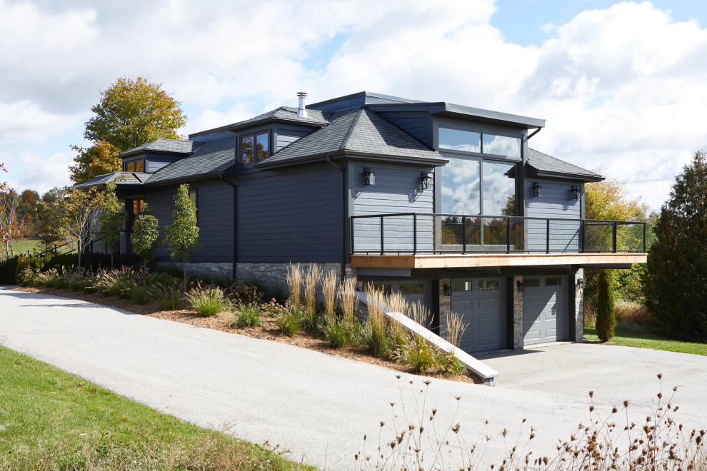 Стильный дизайн: большой, синий, деревянный частный загородный дом в стиле неоклассика (современная классика) с разными уровнями, крышей из гибкой черепицы, черной крышей, отделкой планкеном и мансардной крышей - последний тренд