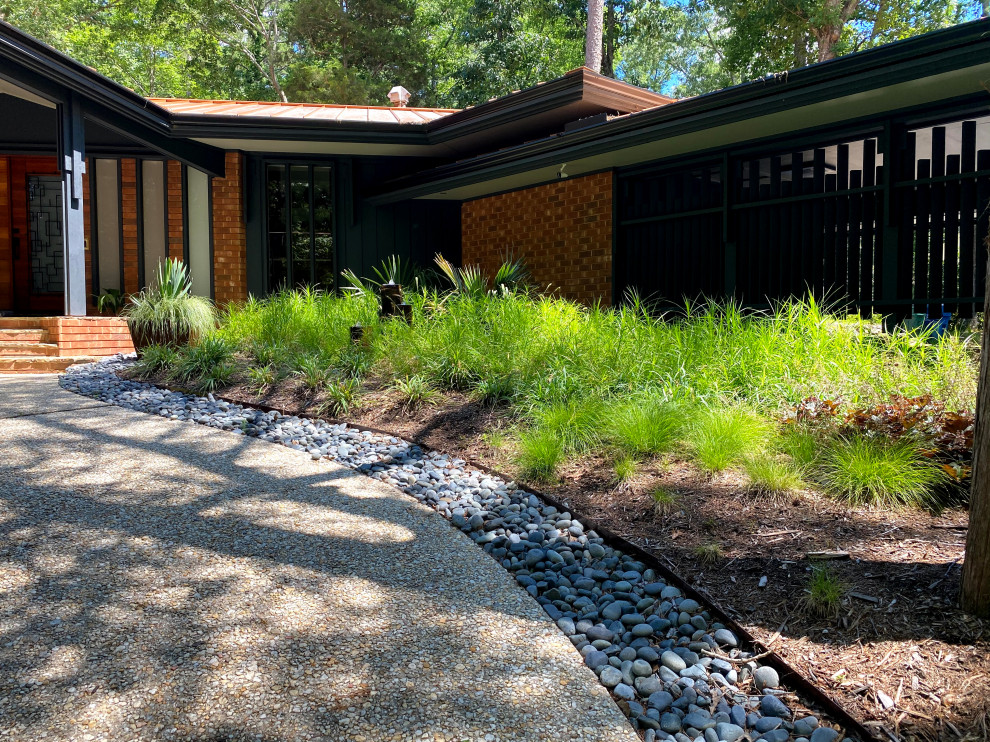 Large midcentury front yard partial sun xeriscape in Raleigh with with waterfall and river rock.