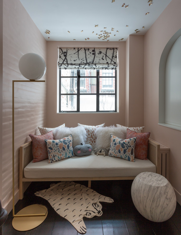 This is an example of a small contemporary nursery for girls in New York with pink walls, dark hardwood floors and black floor.