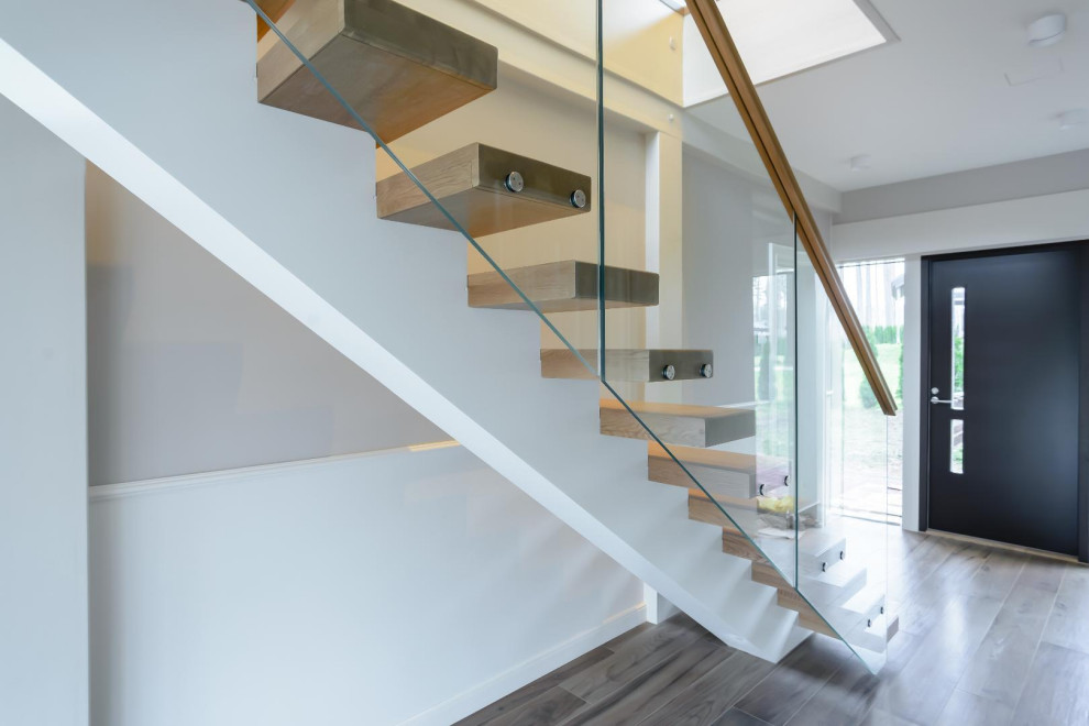 Свежая идея для дизайна: прямая лестница среднего размера в современном стиле с деревянными ступенями и стеклянными перилами без подступенок - отличное фото интерьера