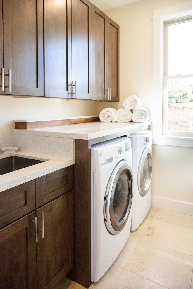 Design ideas for a mid-sized contemporary single-wall dedicated laundry room in Hawaii with an undermount sink, shaker cabinets, quartz benchtops, white walls, travertine floors, a side-by-side washer and dryer, beige floor and dark wood cabinets.