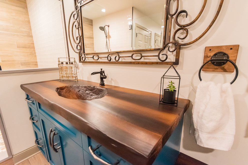 This is an example of a mid-sized country 3/4 bathroom in Philadelphia with shaker cabinets, turquoise cabinets, an alcove shower, a one-piece toilet, beige tile, beige walls, porcelain floors, a console sink, concrete benchtops, brown floor, a hinged shower door and brown benchtops.