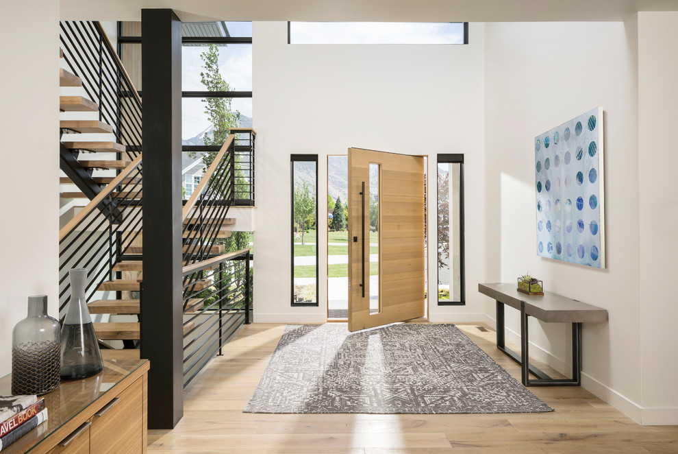 Expansive contemporary front door in Salt Lake City with white walls, light hardwood floors, a single front door, a light wood front door and beige floor.