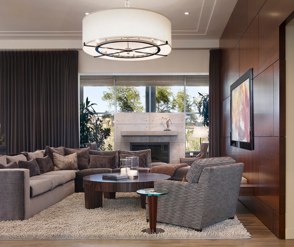 This is an example of a large contemporary open concept family room in Las Vegas with a concrete fireplace surround, light hardwood floors, multi-coloured walls, a standard fireplace and no tv.