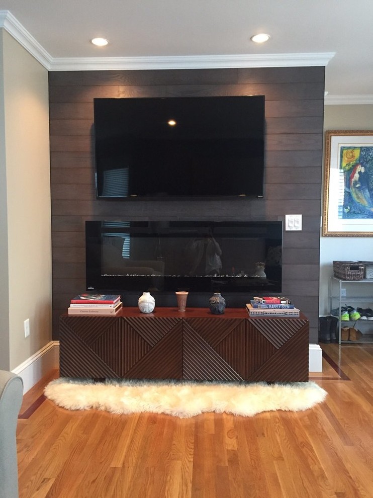 This is an example of a mid-sized contemporary open concept living room in Boston with beige walls, light hardwood floors, a ribbon fireplace, a metal fireplace surround, a wall-mounted tv and beige floor.