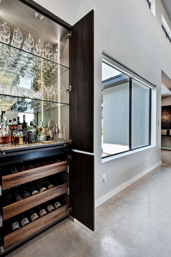 This is an example of a mid-sized contemporary l-shaped home bar in Austin with an undermount sink, flat-panel cabinets, grey cabinets, quartz benchtops, white splashback, marble splashback, concrete floors, grey floor and white benchtop.