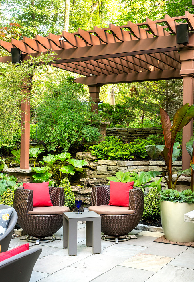 Inspiration for a mid-sized tropical courtyard patio in Montreal with natural stone pavers and a pergola.