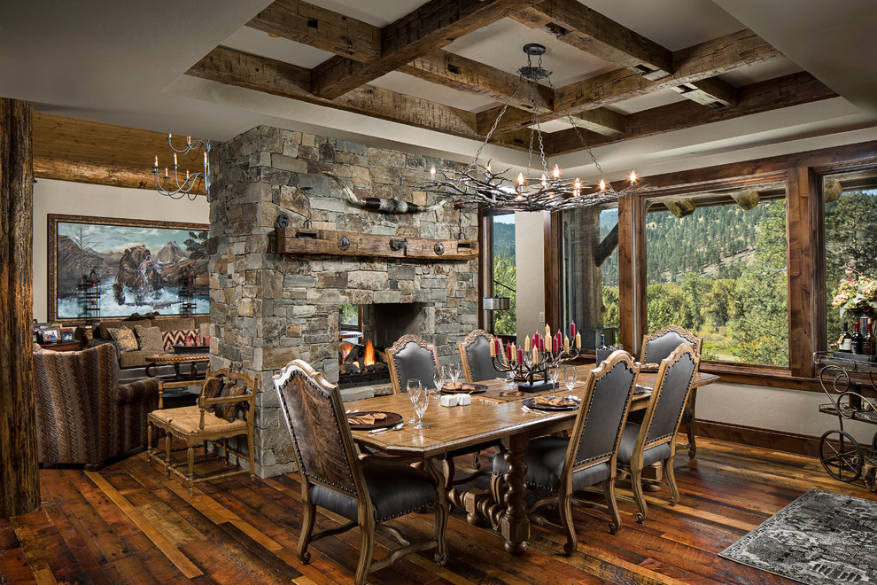 Photo of a large country dining room in Other with white walls, dark hardwood floors, a two-sided fireplace and a stone fireplace surround.