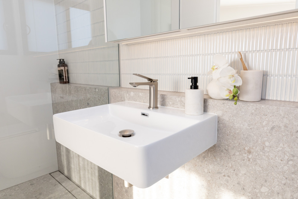 Inspiration for a small contemporary master bathroom in Sydney with a curbless shower, white tile, matchstick tile, porcelain floors, a wall-mount sink, grey floor, an open shower, a niche, a single vanity and vaulted.