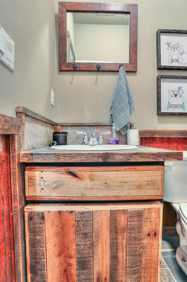 Photo of a small country bathroom in Other with distressed cabinets, flat-panel cabinets, a one-piece toilet, a drop-in sink, stainless steel benchtops and grey benchtops.
