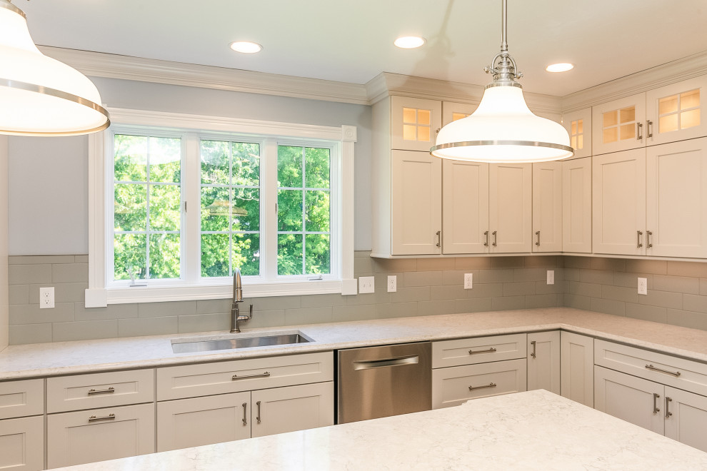 Inspiration for a large transitional l-shaped light wood floor open concept kitchen remodel in Boston with an undermount sink, flat-panel cabinets, white cabinets, quartz countertops, gray backsplash, ceramic backsplash, stainless steel appliances, an island and gray countertops