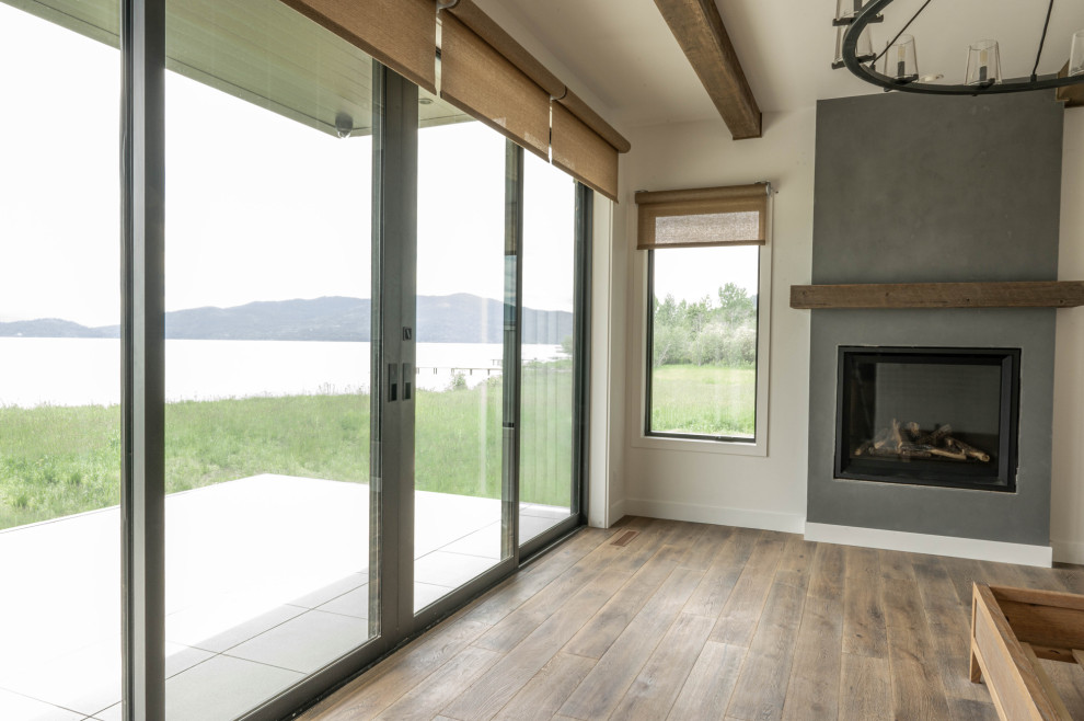 This is an example of a modern open concept living room in Boise with white walls, medium hardwood floors, a standard fireplace and brown floor.