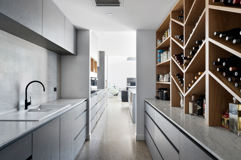 Large contemporary single-wall open plan kitchen in Melbourne with an undermount sink, quartz benchtops, black appliances, concrete floors and with island.