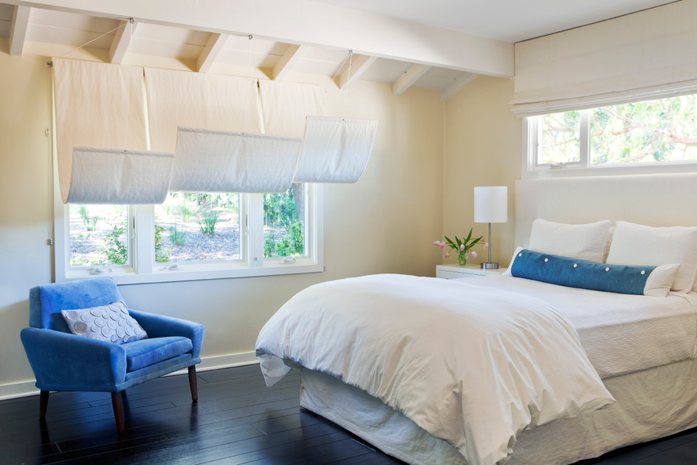 Design ideas for a beach style master bedroom in Santa Barbara with beige walls, dark hardwood floors and black floor.