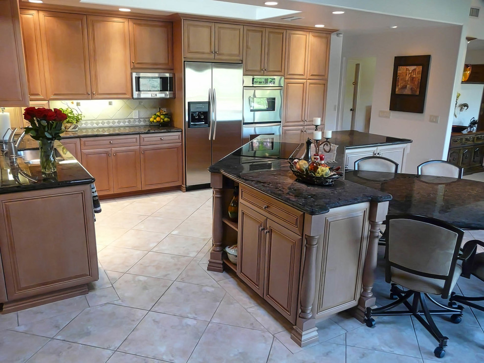 Inspiration for an expansive transitional l-shaped open plan kitchen in San Diego with an undermount sink, raised-panel cabinets, medium wood cabinets, granite benchtops, beige splashback, stone tile splashback, stainless steel appliances, porcelain floors and with island.