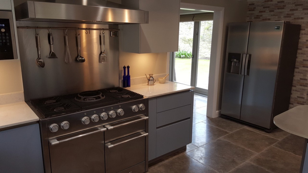 Mid-sized modern u-shaped eat-in kitchen in Oxfordshire with flat-panel cabinets, grey cabinets, quartzite benchtops, multi-coloured splashback, terra-cotta splashback, cement tiles, a peninsula, brown floor and white benchtop.