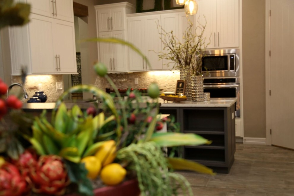Small transitional u-shaped light wood floor open concept kitchen photo in Orange County with an undermount sink, louvered cabinets, white cabinets, solid surface countertops, beige backsplash, stone tile backsplash, stainless steel appliances and two islands