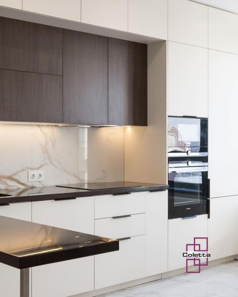 Photo of a mid-sized modern u-shaped eat-in kitchen in Moscow with an integrated sink, flat-panel cabinets, beige cabinets, solid surface benchtops, beige splashback, granite splashback, black appliances, porcelain floors, a peninsula, white floor, black benchtop and vaulted.