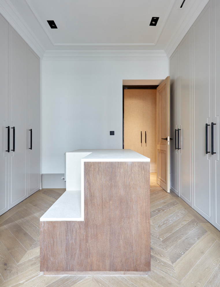 Large transitional gender-neutral walk-in wardrobe in Madrid with beaded inset cabinets, grey cabinets, light hardwood floors, multi-coloured floor and recessed.