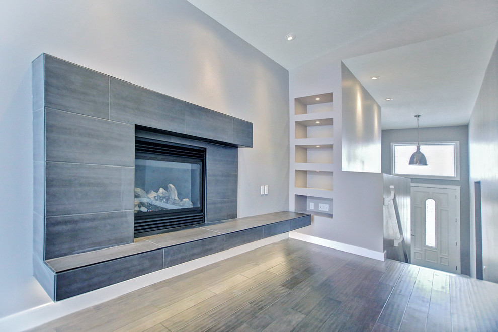 Contemporary open concept living room in Other with grey walls and a tile fireplace surround.