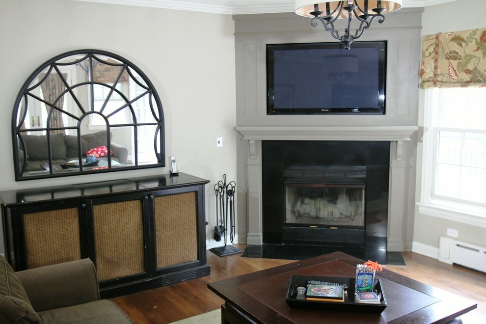 This is an example of a small traditional enclosed family room in Chicago with grey walls, medium hardwood floors, a corner fireplace, a stone fireplace surround and a built-in media wall.