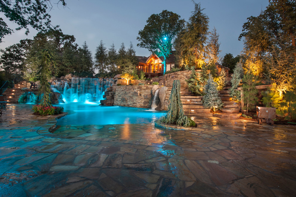 Inspiration for an expansive country backyard custom-shaped natural pool in Oklahoma City with a water feature and natural stone pavers.