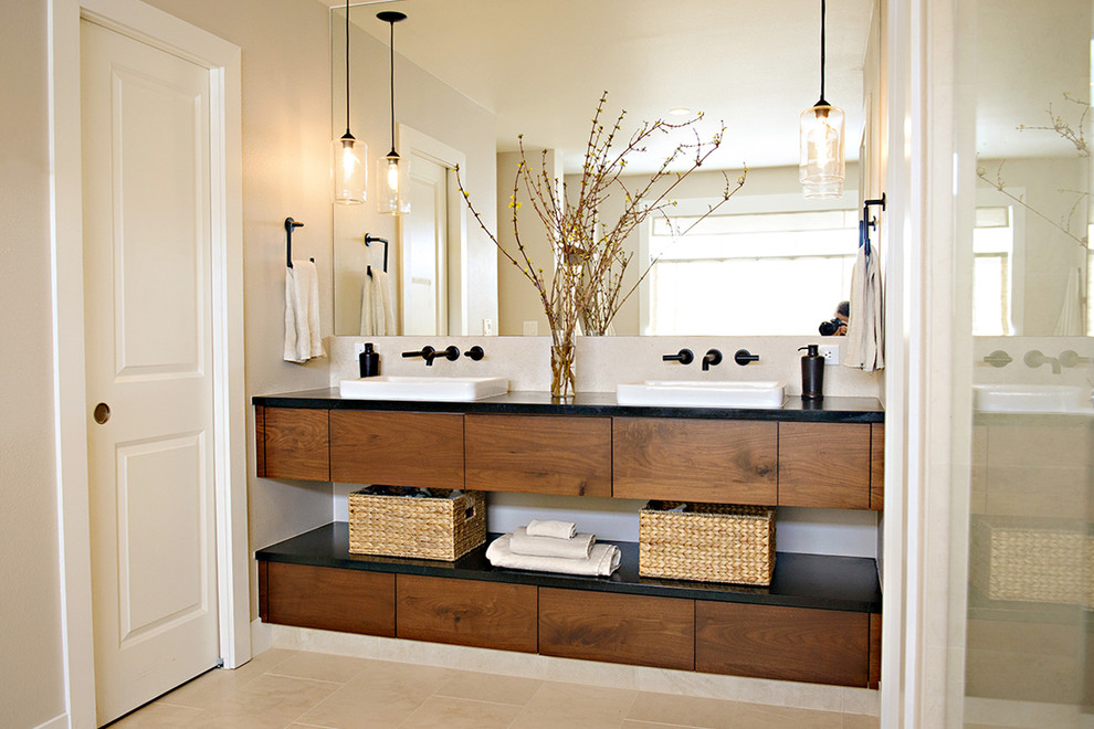 Design ideas for a large contemporary master bathroom in Denver with flat-panel cabinets, dark wood cabinets, an undermount tub, beige tile, stone tile, beige walls, limestone floors, a vessel sink and soapstone benchtops.