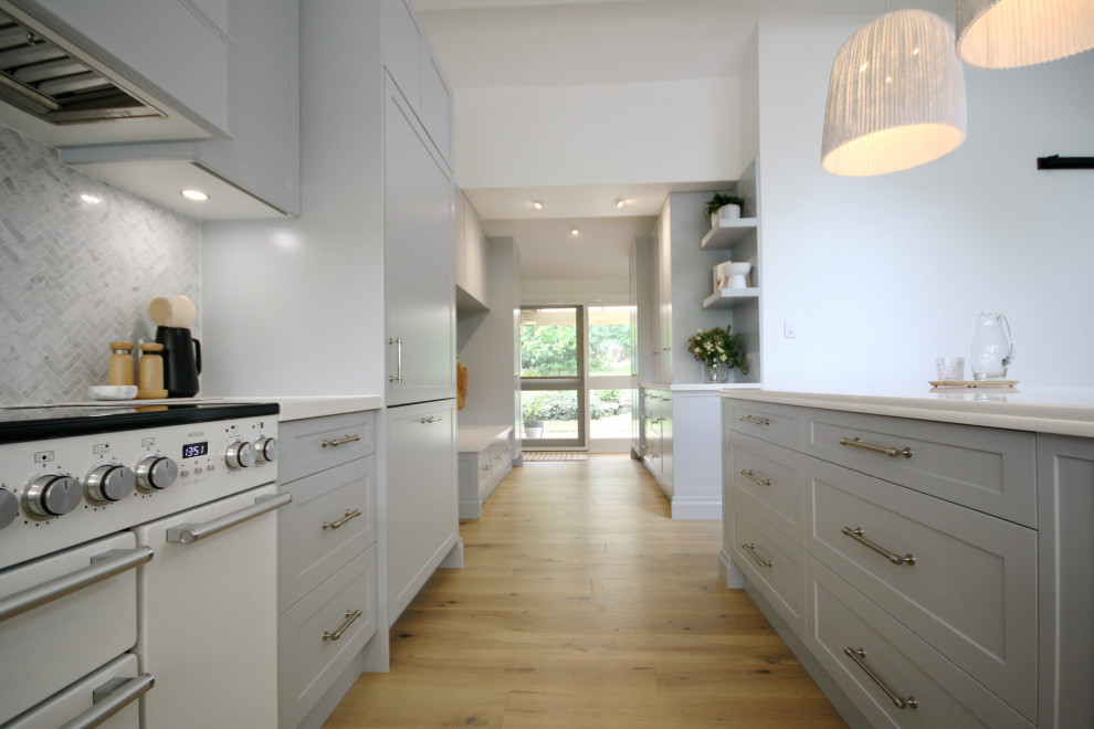 Exempel på ett mycket stort klassiskt vit vitt kök med öppen planlösning, med en rustik diskho, skåp i shakerstil, grå skåp, bänkskiva i kvarts, grått stänkskydd, stänkskydd i marmor, vita vitvaror, mellanmörkt trägolv, en köksö och brunt golv