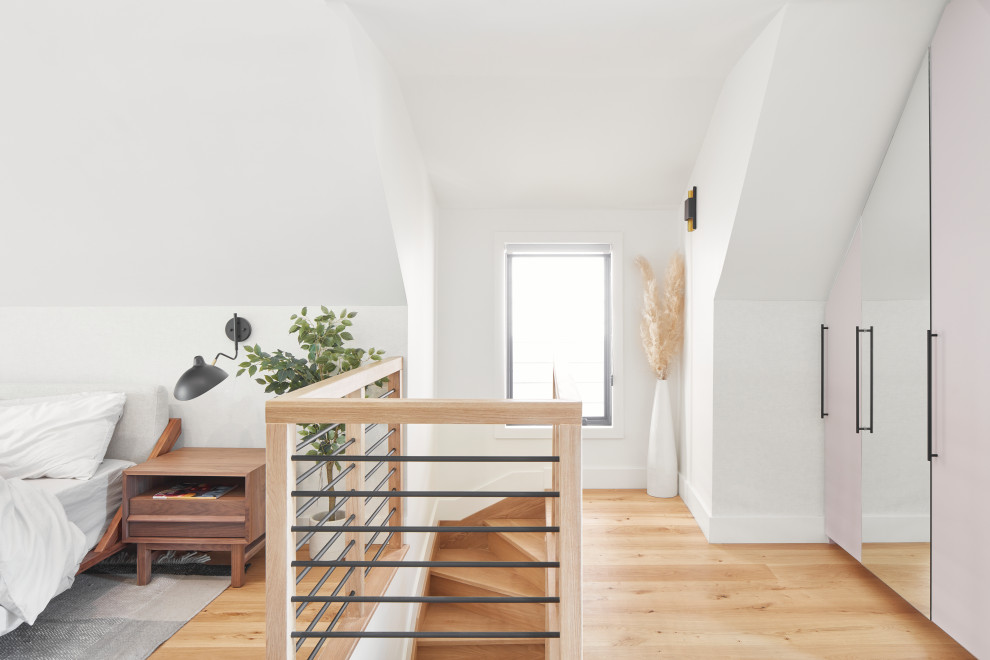 Immagine di un'In mansarda camera da letto stile loft moderna di medie dimensioni con pareti bianche, parquet chiaro, pavimento beige, soffitto a volta e carta da parati