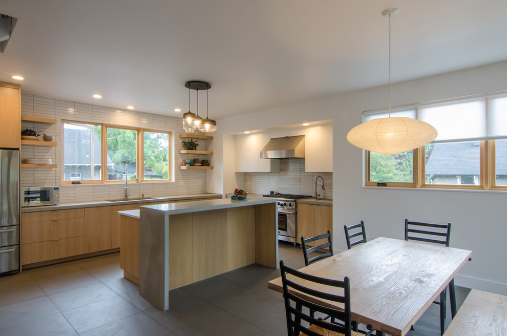 Large transitional l-shaped eat-in kitchen in Portland with a single-bowl sink, flat-panel cabinets, light wood cabinets, white splashback, ceramic splashback, stainless steel appliances, with island, black floor, grey benchtop, concrete benchtops and porcelain floors.