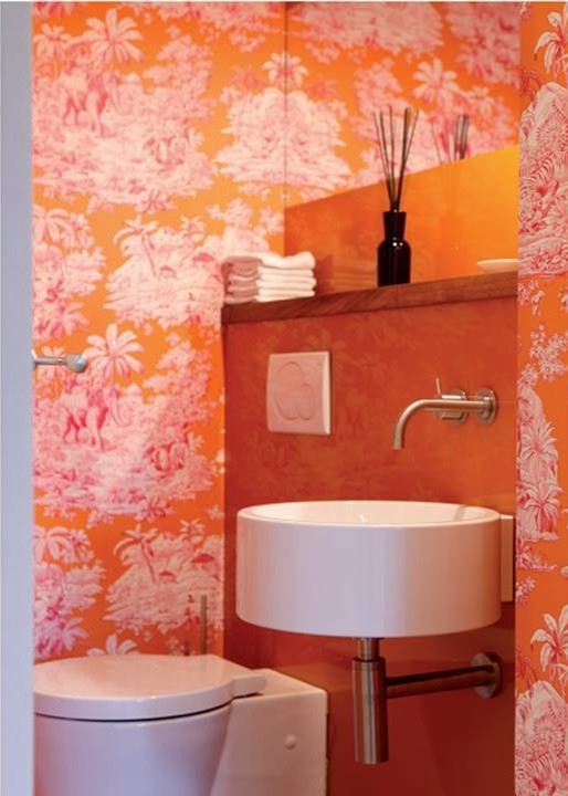 Inspiration for a small contemporary powder room in Frankfurt with a wall-mount sink, wood benchtops, a wall-mount toilet, ceramic tile and orange walls.