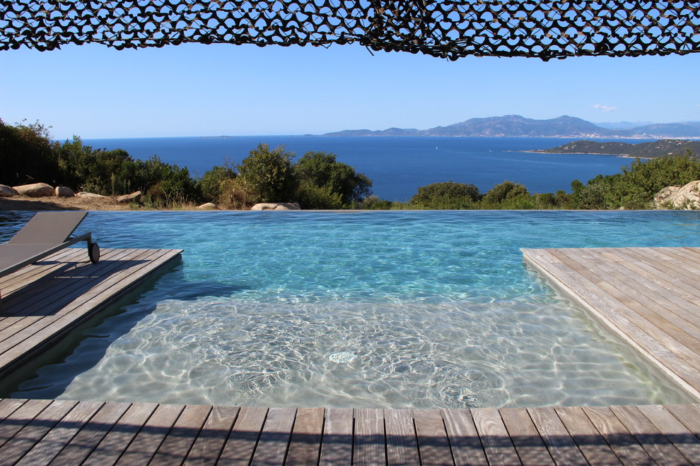 Photo of a mid-sized beach style front yard custom-shaped infinity pool in Corsica.