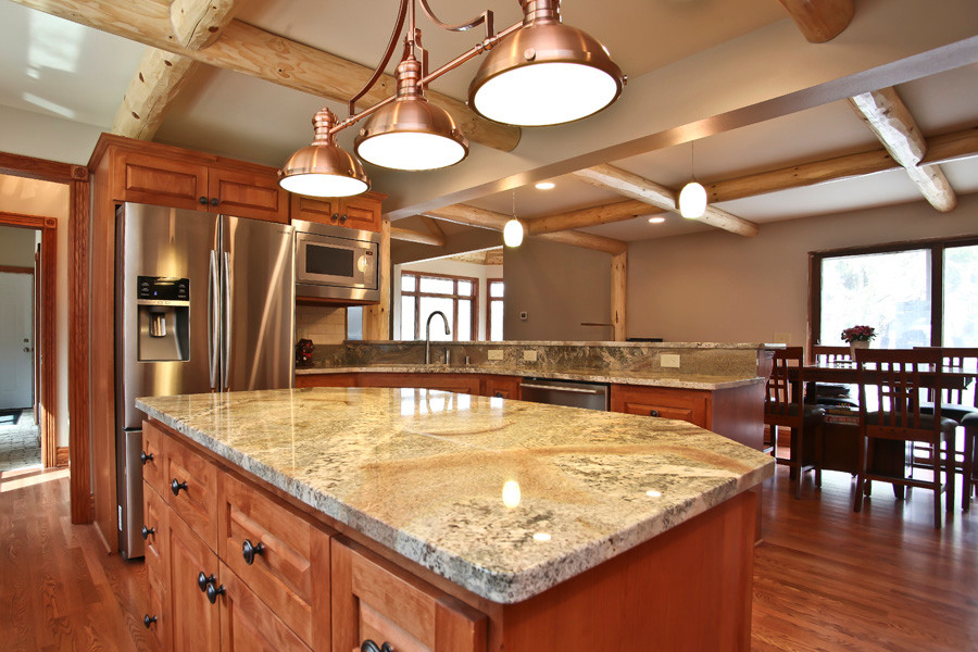 Large mountain style u-shaped medium tone wood floor eat-in kitchen photo in Milwaukee with a single-bowl sink, shaker cabinets, medium tone wood cabinets, granite countertops, beige backsplash, ceramic backsplash, stainless steel appliances and an island