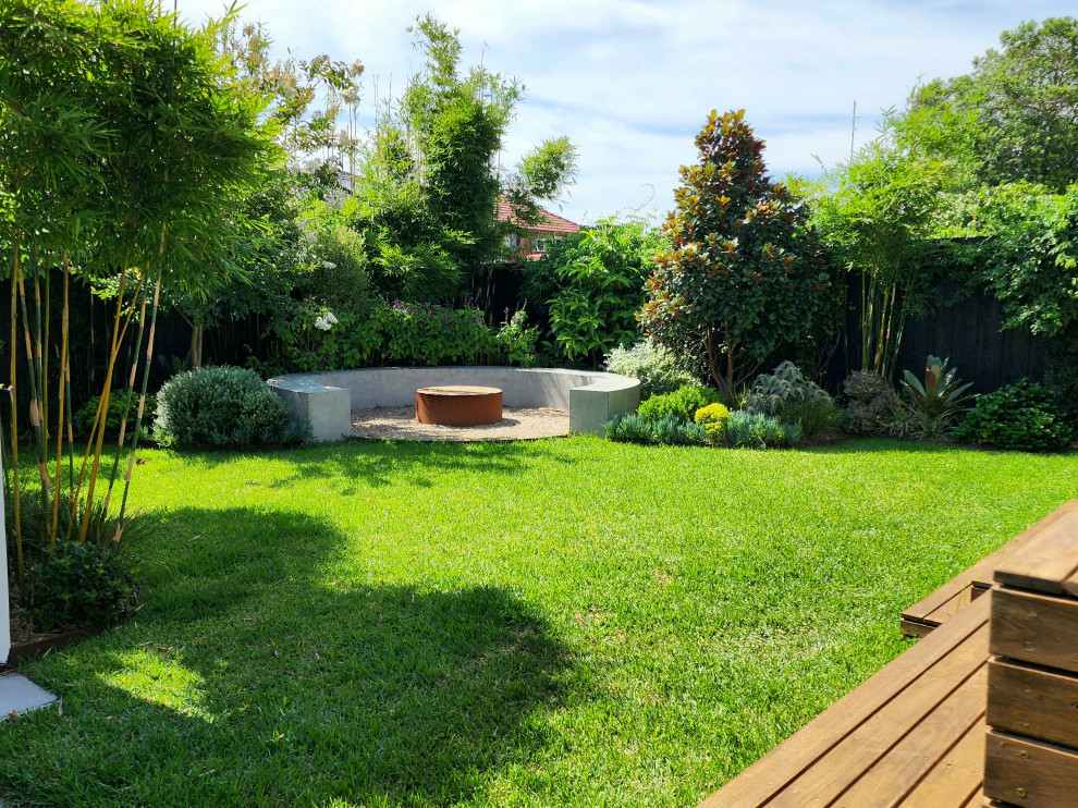 Пример оригинального дизайна: большой солнечный, осенний участок и сад на заднем дворе в современном стиле с местом для костра, хорошей освещенностью, покрытием из каменной брусчатки и с деревянным забором